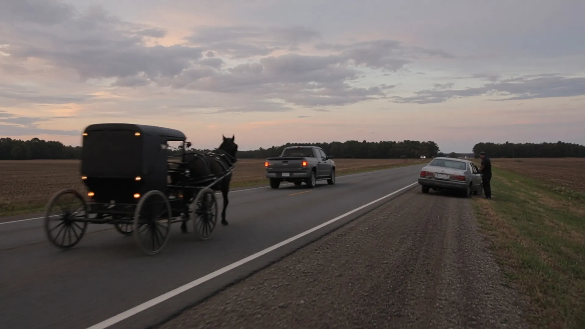 Hopkinsville, KY personal injury lawyer — Horse-drawn buggy at the edge of a rural highway as a pickup slows and a driver checks a damaged car near Hopkinsville