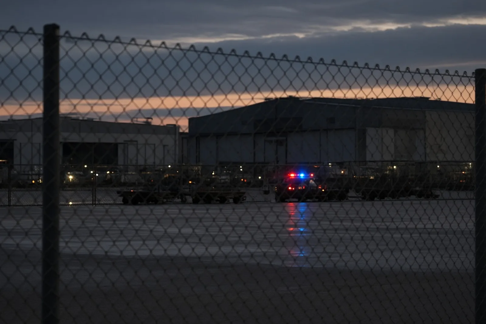 Airport cargo area at dusk with emergency lights in the distance after the UPS Flight 2976 crash